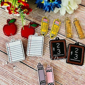 May include: A set of 10 colourful school-themed earrings. The earrings feature a red apple, a yellow pencil, a ruler, a sheet of paper, a chalkboard, and a crayon.