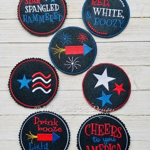 May include: Set of 6 round black felt coasters with red, white, and blue embroidered designs. The designs include fireworks, stars, and text such as "Star Spangled Hammered", "Red, White, Boozy", "Drink Booze Light Fuse", and "Cheers to You America".