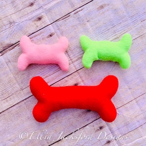 May include: Three felt dog bone toys in different sizes. The largest bone is red, the medium bone is green, and the smallest bone is pink.
