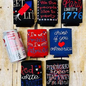 May include: Ten black and white can coolers with red, white, and blue embroidered designs. The designs include phrases like "Get Lit", "We the people like to party", "Party Like It's 1776", "I'm not Drunk I'm Patriotic", "Drink if you love America", "Red White & Boozed", and "Fireworks & Beer That's Why I'm Here".