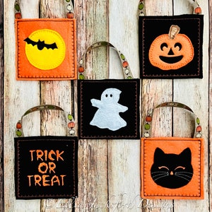 May include: Five felt Halloween treat bags in orange and black fabric. The bags feature a bat, ghost, pumpkin, cat, and the words "trick or treat".