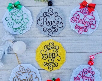 Può includere: Sei ornamenti natalizi ricamati con diversi saluti festivi. Gli ornamenti sono bianchi, grigi, rossi, gialli e verdi con ricami neri, dorati e rossi. Gli ornamenti presentano le parole "Noël", "Pace", "Credere", "Gioia", "Cristo" e "Buon Natale".