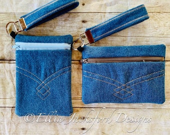 May include: Two denim zipper pouches with a denim wrist strap and a silver key ring. The pouches have a diamond-shaped design stitched in brown thread. The pouches are on a wooden surface.