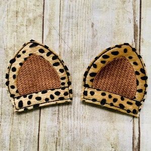 May include: A pair of brown and black cheetah print fabric ear headbands with a brown mesh inner lining.