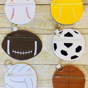 May include: Six different sports ball-shaped zipper pouches with key rings. The pouches are made of felt and feature a variety of sports ball designs, including baseball, tennis, football, soccer, volleyball, and basketball.