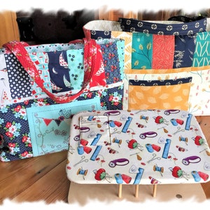 May include: Three colorful fabric tote bags with different patterns and a white fabric ironing board cover with a sewing themed pattern.