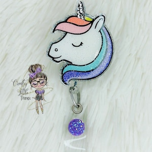 May include: A sparkly white unicorn head with a rainbow mane and a silver glitter background. The unicorn is attached to a retractable badge holder with a purple glitter button and a clear plastic badge holder.