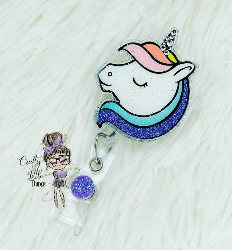 May include: A sparkly unicorn head badge reel with a blue, pink and white glitter design. The reel has a clear plastic backing and a purple glitter charm.