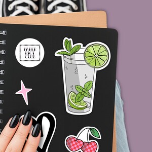 Tropical vacation vibes green mojito cocktail with lime and mint garnish die-cut vinyl sticker stuck to the front of a journal.