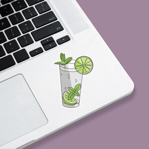 Tropical vacation vibes green mojito cocktail with lime and mint garnish die-cut vinyl sticker stuck to a laptop.