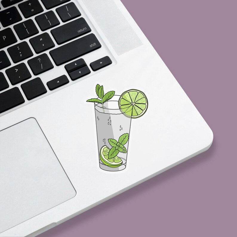Tropical vacation vibes green mojito cocktail with lime and mint garnish die-cut vinyl sticker stuck to a laptop.