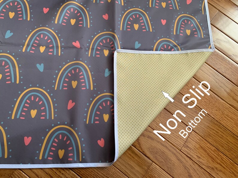 May include: A gray play mat with a rainbow and heart pattern. The mat has a white border and a non-slip bottom.