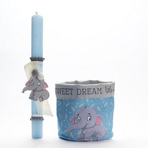 Puede incluir: Una cesta de regalo de baby shower azul y gris con una vela azul y un diseño de elefante gris. La cesta tiene el texto "Sweet Dream little one" en ella.