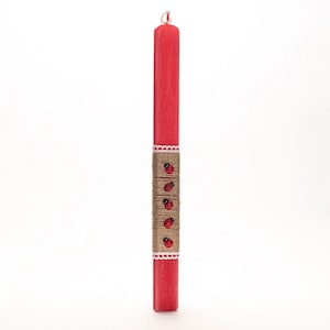 Puede incluir: Una vela de Pascua roja con un borde de encaje blanco y una banda de cuerda marrón decorada con mariquitas rojas.