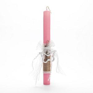 Puede incluir: Una vela de Pascua rosa con una cinta de encaje blanca y una decoración de mariposa plateada.