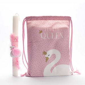 Puede incluir: Una bolsa de cordón rosa con lunares blancos y un cisne blanco con una corona dorada. La bolsa tiene el texto "Little Queen" impreso. Una vela en forma de cisne rosa y blanco con plumas rosas está al lado de la bolsa.