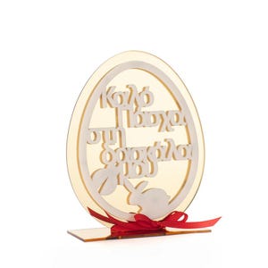 Puede incluir: Adorno decorativo en forma de huevo de Pascua de color dorado claro. El adorno presenta texto griego blanco y una silueta de conejo. Una cinta roja está atada en la base. Diseñado para celebraciones de Pascua.