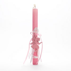 Puede incluir: Vela de Pascua rosa con una cinta de encaje blanco y una figurita de hada rosa adjunta. El hada tiene un ala de encaje blanco y el texto "Feliz Pascua" escrito en ella.