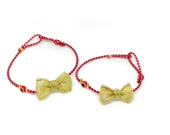 May include: Two red and white string bracelets with gold bows and blue evil eye charms.