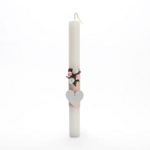 Puede incluir: Una vela blanca con un diseño floral rosa y blanco y una etiqueta en forma de corazón blanca. La vela está decorada con una cinta rosa y blanca.
