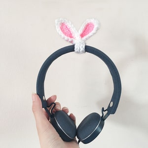 May include: A pair of black headphones with a white crocheted bunny ear headband.