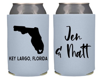 May include: Two light blue can coolers. One cooler features a black silhouette of the state of Florida with a small heart in the center and the text "KEY LARGO, FLORIDA". The other cooler features the text "Jen & Matt" in black cursive.