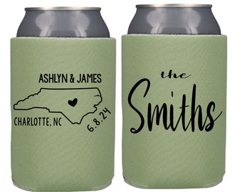 May include: Two green can coolers with personalized text. The left cooler features a map of North Carolina with a heart in the center and the text "Ashlyn & James, Charlotte, NC, 6.8.24". The right cooler features the text "the Smiths".