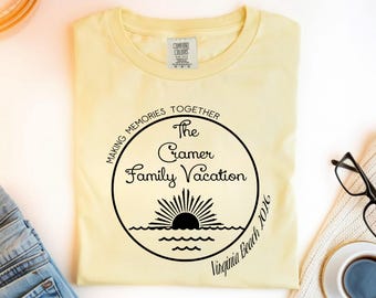 May include: A light yellow t-shirt with a black graphic design. The design includes the text "Making Memories Together The Cramer Family Vacation Virginia Beach 2026" around a circular image of a sun rising over the ocean.