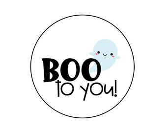 Può includere: Un cerchio bianco con un contorno nero e il testo "BOO to you!" in nero. Un piccolo fantasma bianco con un contorno blu e guance rosa è a destra del testo.