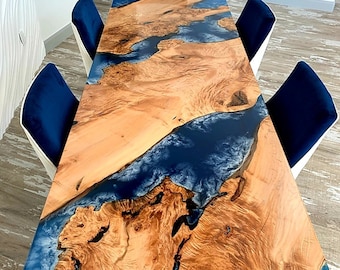 Pode incluir: Uma grande mesa de jantar de madeira com uma incrustação de resina epóxi azul. A mesa é cercada por seis cadeiras de veludo azul.