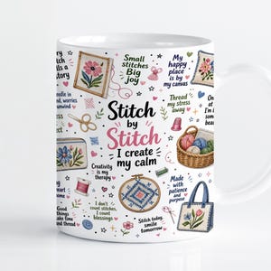 May include: A white ceramic mug featuring a colorful pattern of embroidery hoops, yarn baskets, sewing supplies, and floral designs. The text reads Stitch by Stitch I create my calm, along with phrases like Small stitches Big joy and Made with patience.