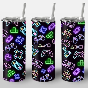 May include: Three stainless steel tumblers with lids and straws. The tumblers are decorated with a neon-coloured pattern of video game controllers, joysticks, and other gaming symbols on a black background.