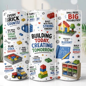 May include: A white cylindrical tumbler with a metal straw featuring colorful illustrations of building blocks, a house, a truck, and a shelf. The design includes motivational text like Every Brick Counts, Building Today, Creating Tomorrow, and Small Pieces, Big Possibilities.
