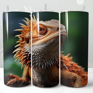 May include: A stainless steel tumbler with a colorful image of a bearded dragon lizard. The lizard is orange and brown with a green background.