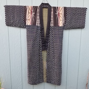 May include: A black and white polka dot kimono with a brown and white patterned panel across the shoulders. The kimono is lined with a green fabric.