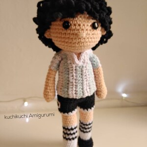 Peut inclure: Poupée de footballeur au crochet faite à la main, avec des cheveux noirs bouclés et une peau claire. La poupée porte un maillot rayé bleu clair et blanc, un short noir et des chaussettes rayées noires et blanches. La poupée mesure environ 25 cm de haut.