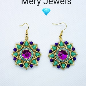 Può includere: Un paio di orecchini pendenti dorati con un centro di cristallo rosa circondato da perline verdi e viola. Gli orecchini sono etichettati "Mery Jewels".
