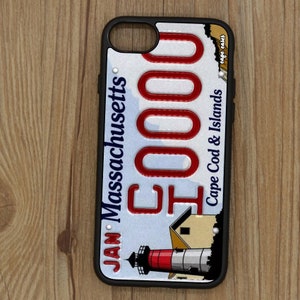 May include: A black iPhone case with a white and blue design featuring a lighthouse and the text "JAN. Massachusetts 50000 Cape Cod & Islands Cape Cods".
