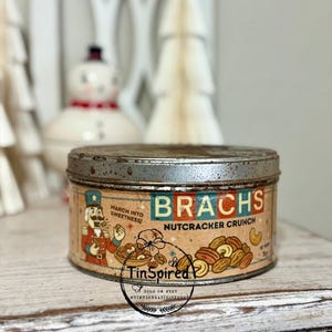 May include: Vintage Brach's Nutcracker Crunch tin with a distressed metal lid and a colorful label. The label features a nutcracker illustration and the text "March into Sweetness!" and "Nutcracker Crunch".