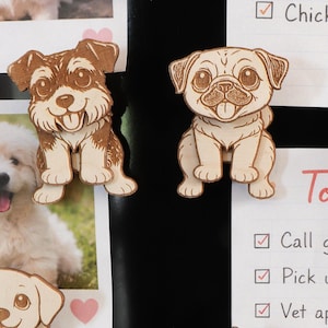 May include: Wooden dog-shaped magnets and a photo of a dog are displayed on a black surface. The magnets are various breeds, including a pug, a Dalmatian, and a golden retriever. A to-do list is also visible, with tasks like "Call groomer" and "Pick up dog food."