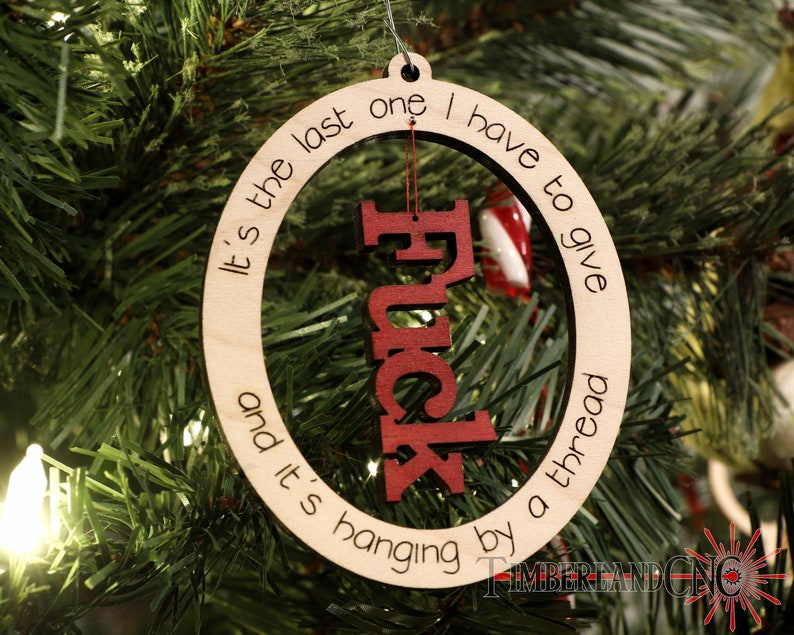 May include: A wooden Christmas ornament with the text "It's the last one I have to give and it's hanging by a thread" and the word "F*ck" in red letters inside the circle.