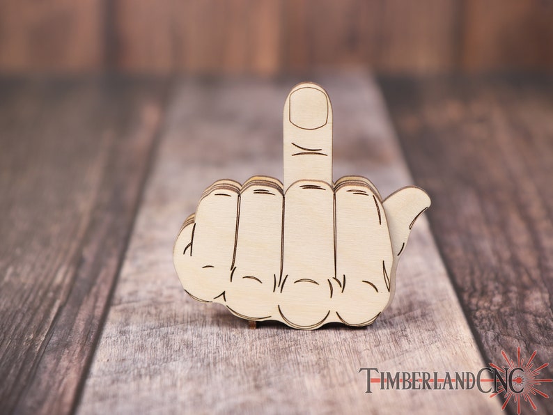 Op de afbeelding: Een houten uitsnijding van een hand die de middelvinger opsteekt. De hand is lichtbruin en heeft een gedetailleerd ontwerp.