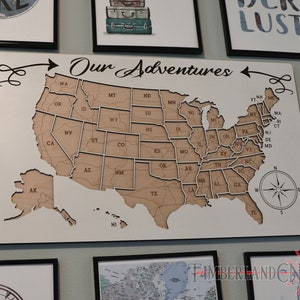 May include: A white wooden map of the United States with the words "Our Adventures" written above it. The map is divided into individual states and includes Alaska and Hawaii. A compass is in the bottom right corner.