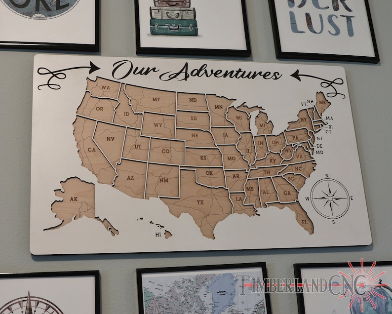 May include: A white wooden map of the United States with the words "Our Adventures" written above it. The map is divided into individual states and includes Alaska and Hawaii. A compass is in the bottom right corner.