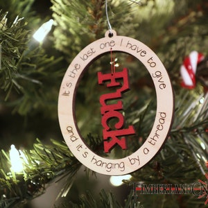 May include: A wooden Christmas ornament with the text "It's the last one I have to give and it's hanging by a thread" and the word "Fuck" in red lettering.
