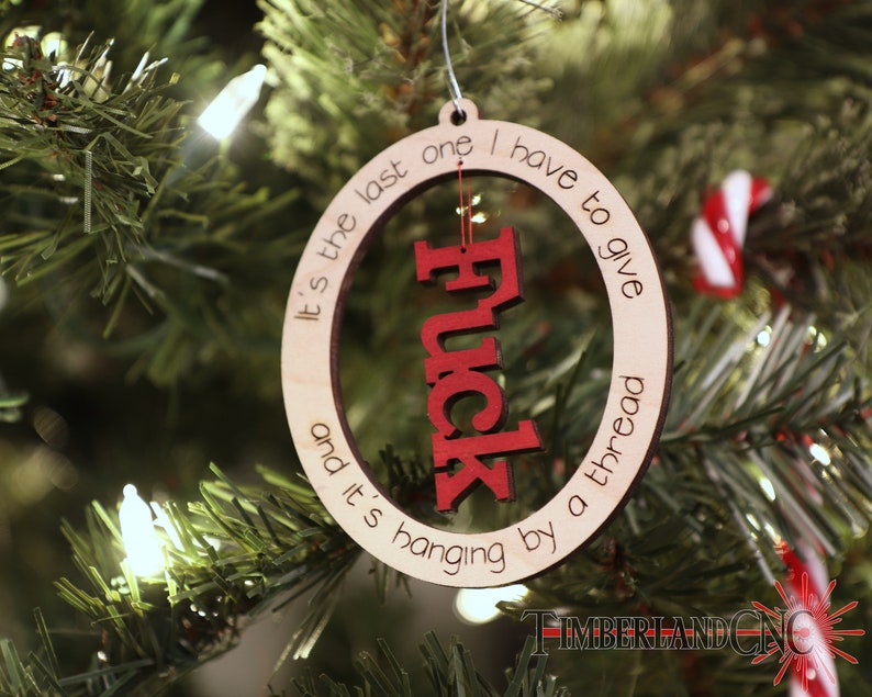 May include: A wooden Christmas ornament with the text "It's the last one I have to give and it's hanging by a thread" and the word "Fuck" in red lettering.
