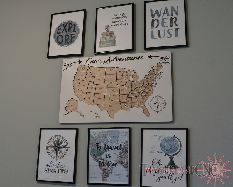 May include: A wall gallery featuring framed prints with travel-themed quotes and images, including a map of the United States, a compass, a globe, and the words "Wanderlust" and "Our Adventures".
