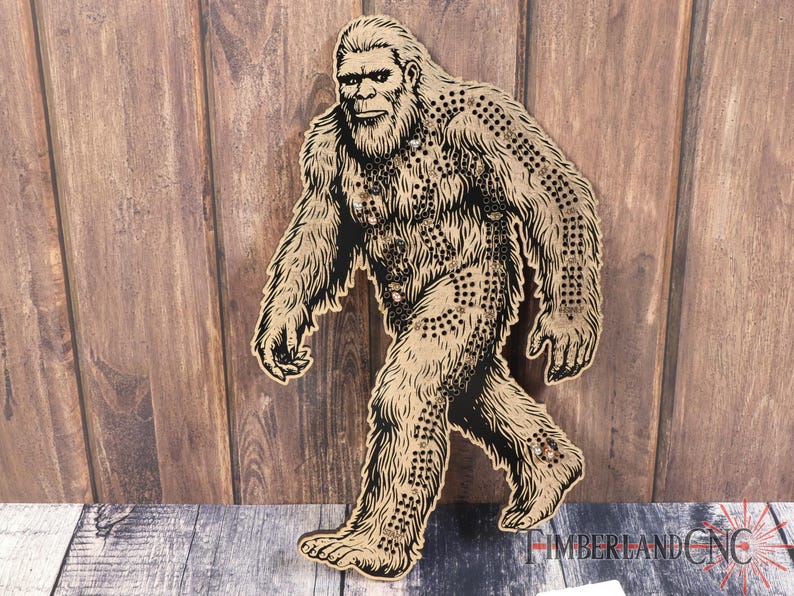 May include: A brown wooden cutout of Bigfoot, a mythical creature, walking with a detailed design of fur and a beard. The cutout is against a woodgrain background.