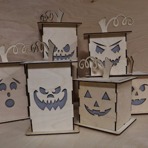 Pode incluir: Um conjunto de seis decorações de abóbora de Halloween de madeira com diferentes rostos esculpidos. As abóboras são feitas de madeira marrom claro e têm um design pintado de branco.