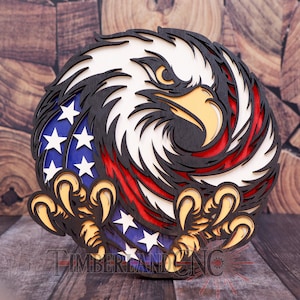 May include: A circular, layered wooden artwork depicting an eagle's head and talons, incorporating the colours and stars of the American flag. The design includes the text "TIMBERLAKE CNC". The eagle's head is white, black, and tan.